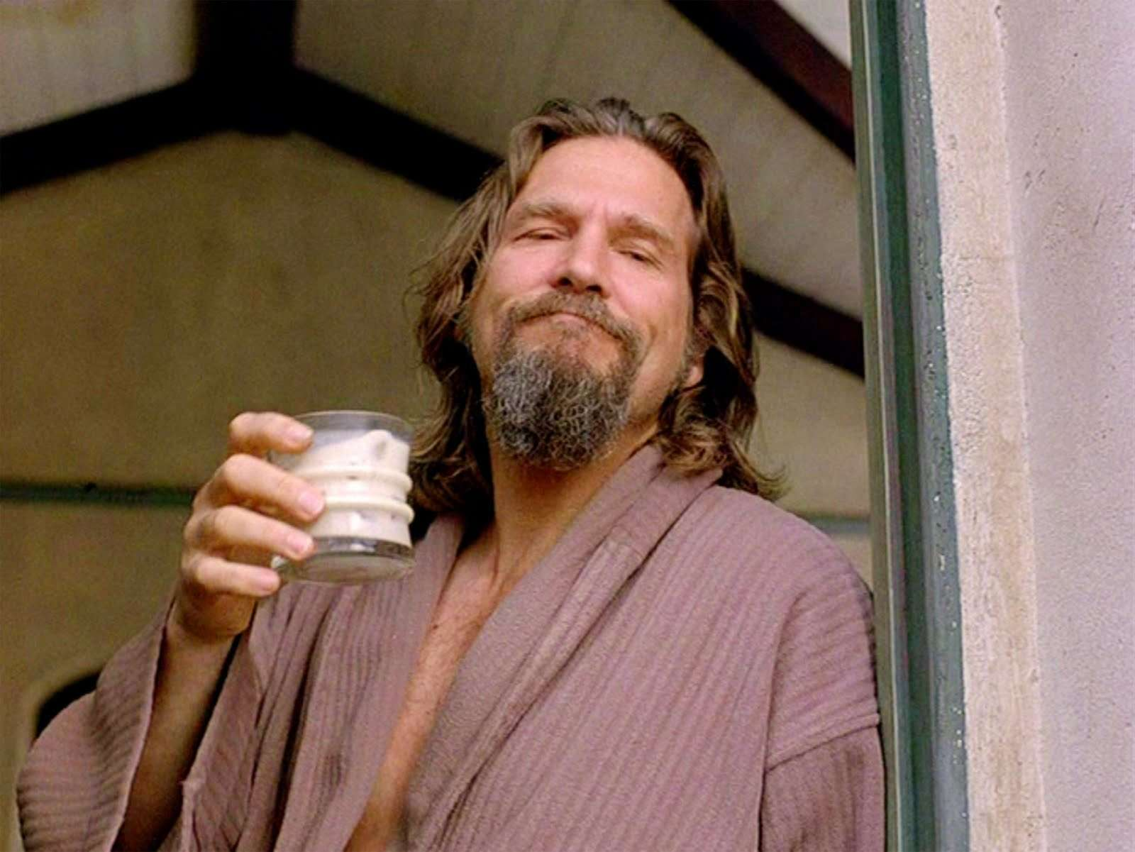 The Dude from The Big Lebowski stands in a doorway while drinking a White Russian